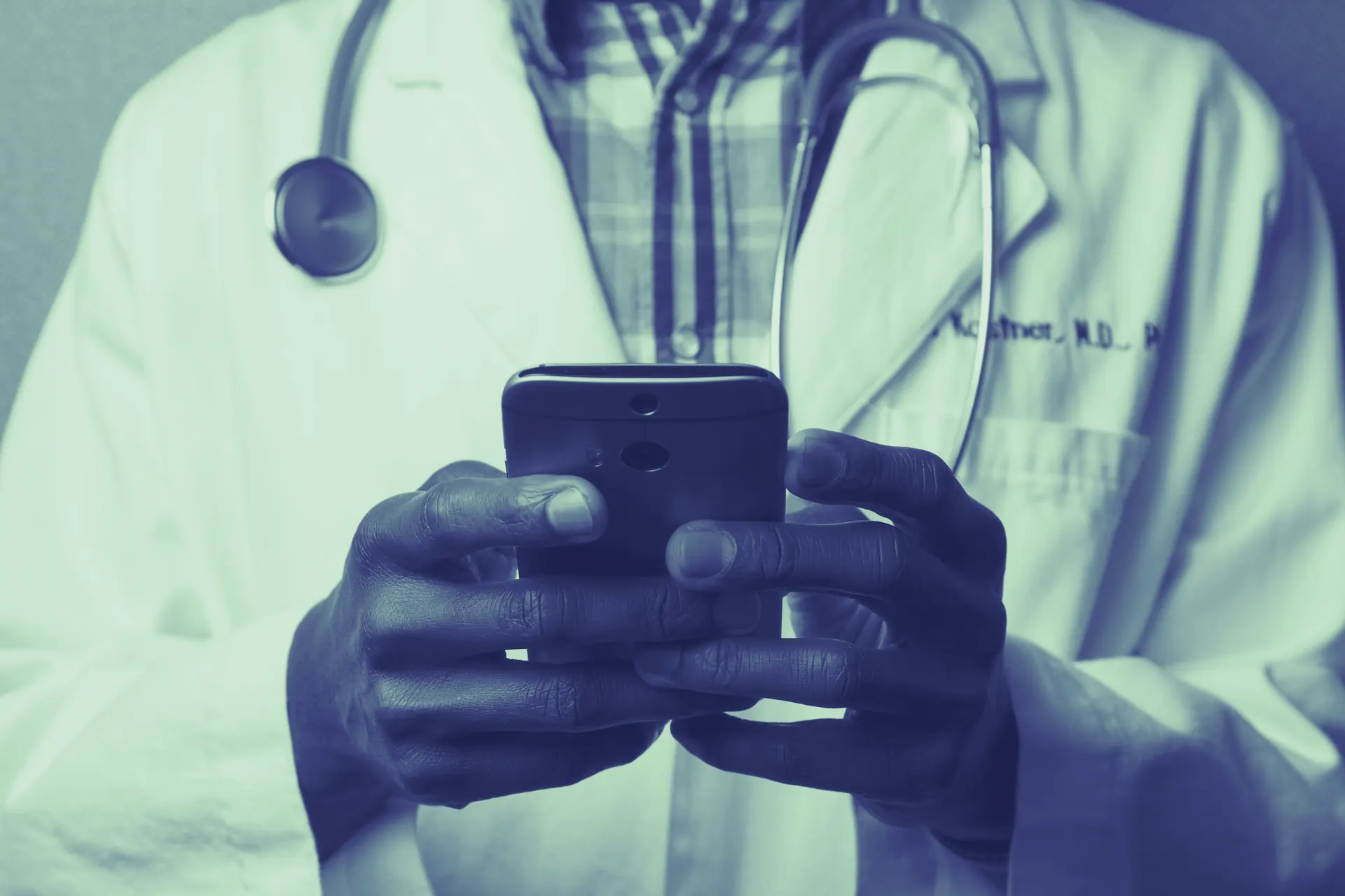 Healthcare professional with a stethoscope using a mobile device
