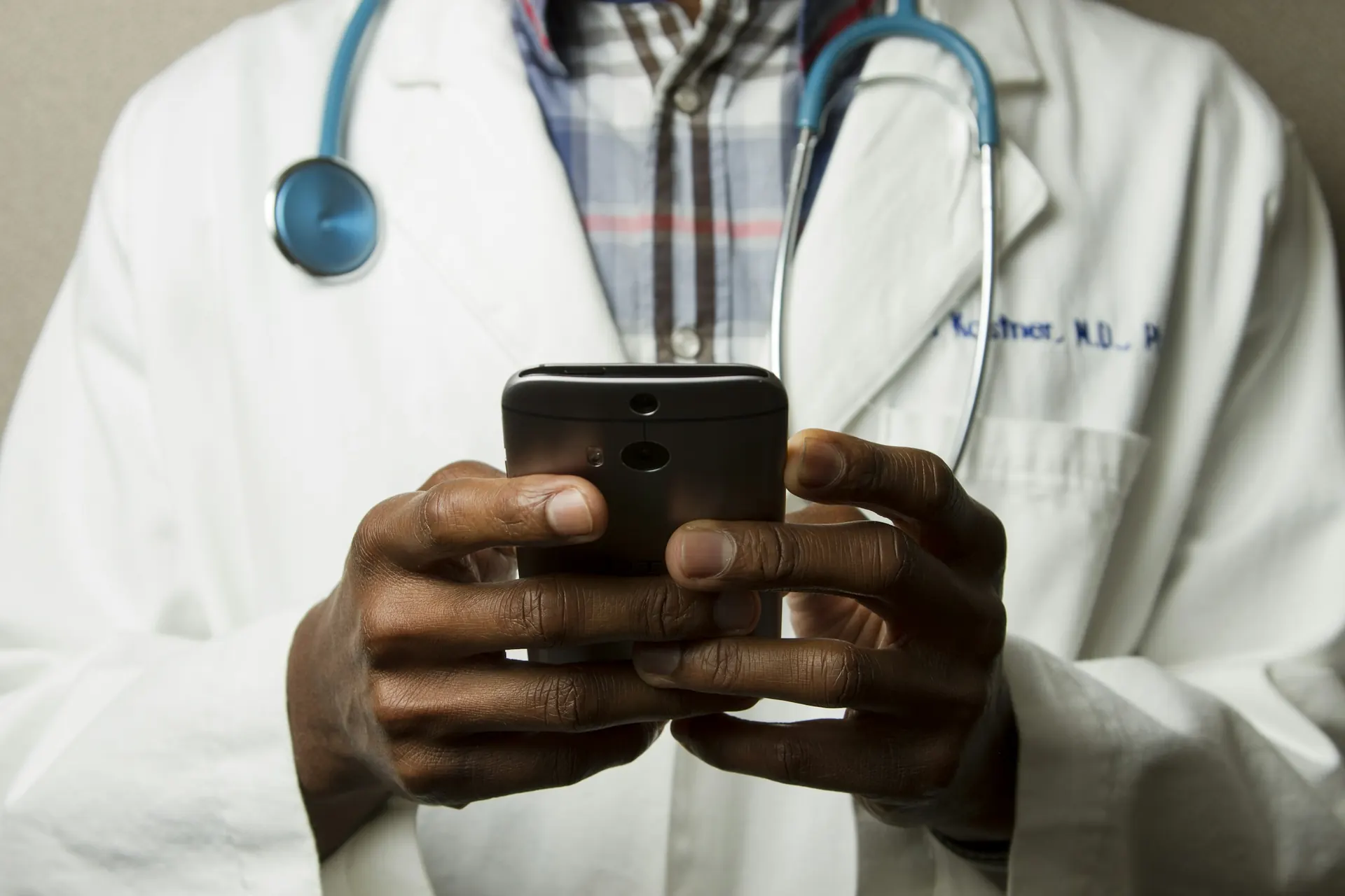 Healthcare professional with a stethoscope using a mobile device